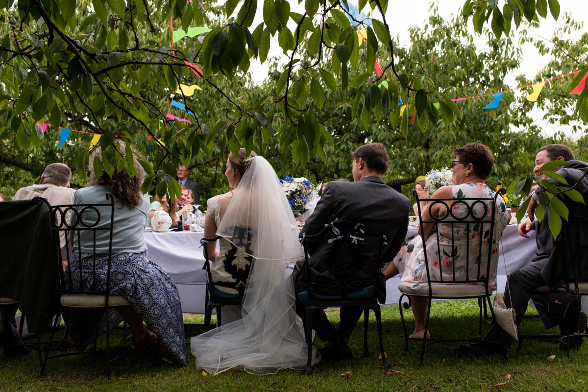 Photograph of Hannah and Matthew at the top table in the orchard for their Kent wedding reception