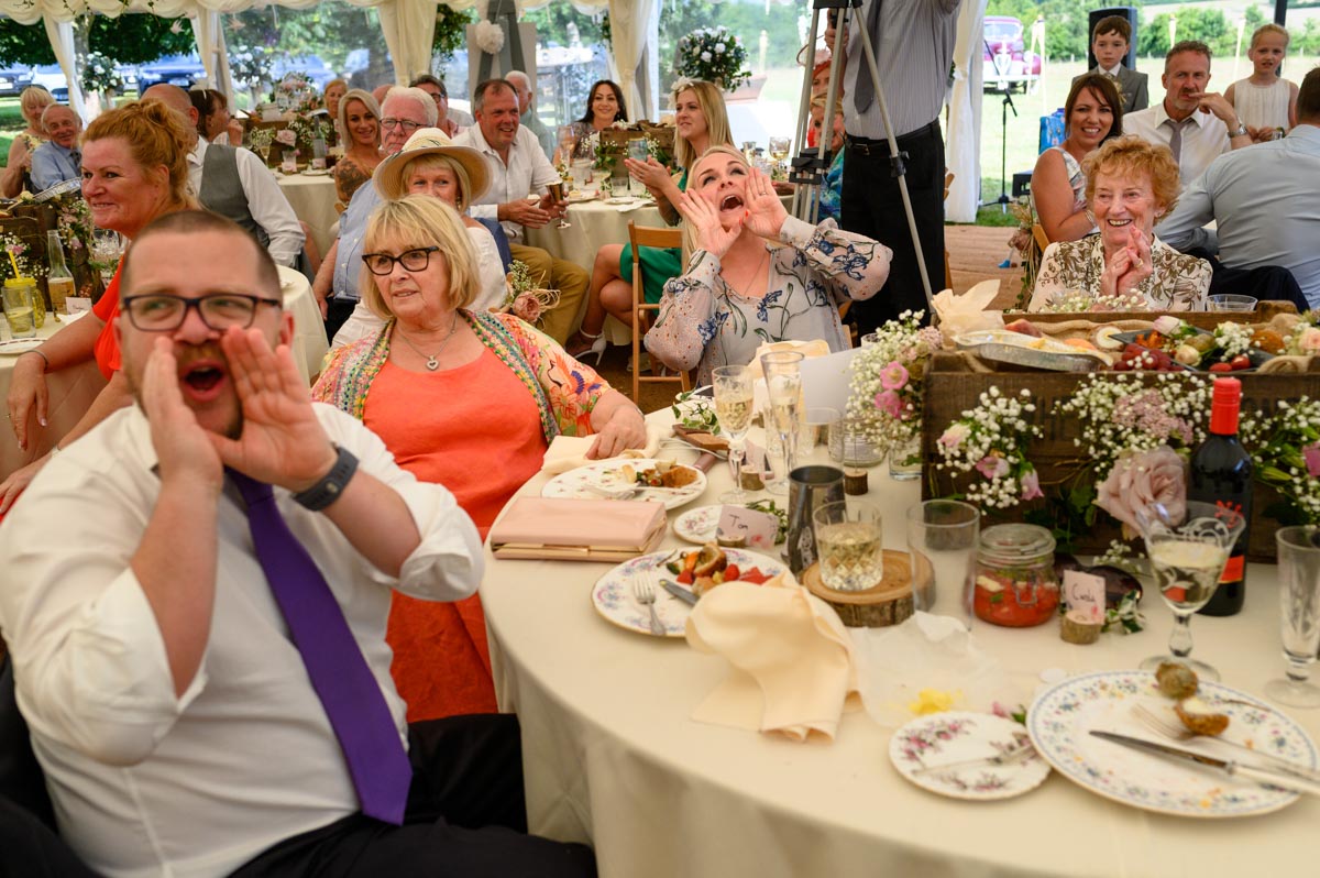 Summer wedding guests enjoy speeches and shout for more
