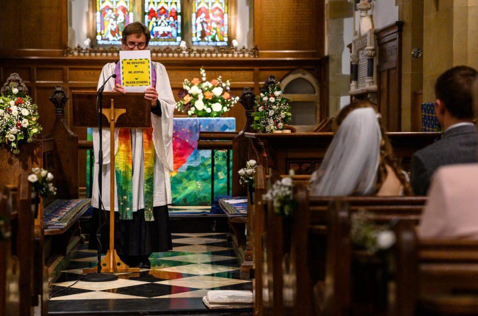 Vicar holds up sign during wedding ceremony marking the pandemic