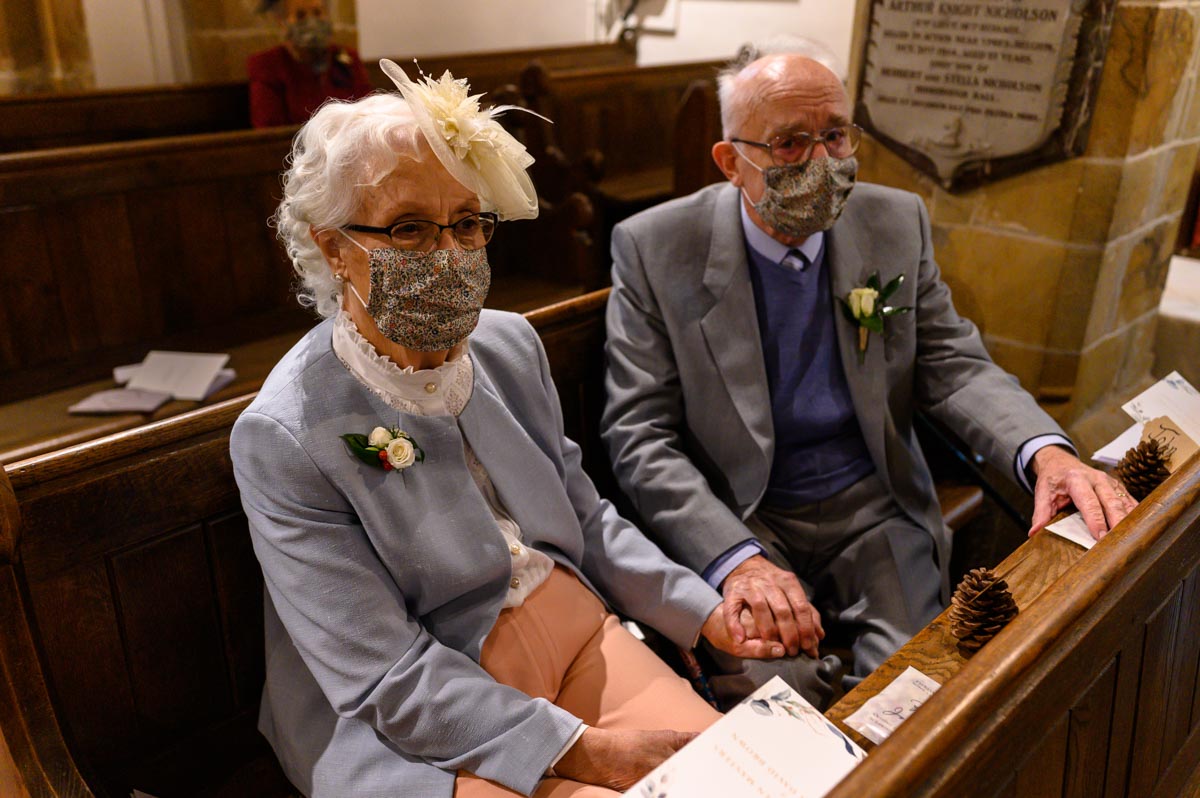 wedding guests wearing masks during church wedding ceremony in covid 19 pandemic