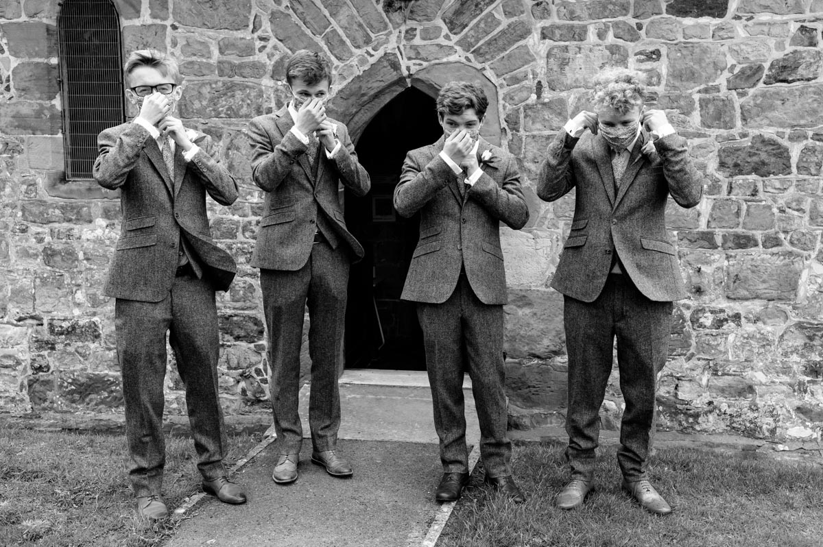 Groom and groomsmen apply their masks outside the church during covid 19 pandemic