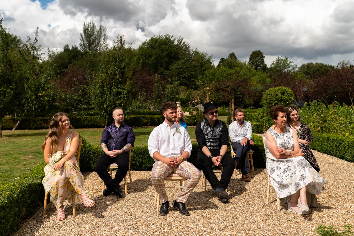 wedding guests sit socially distanced from each other at the secret garden venue in Kent