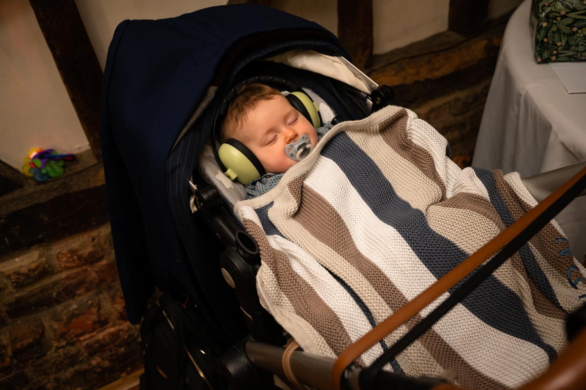 wedding photography best of 2021 photograph of baby sleeping with ear defenders at wedding reception in kent