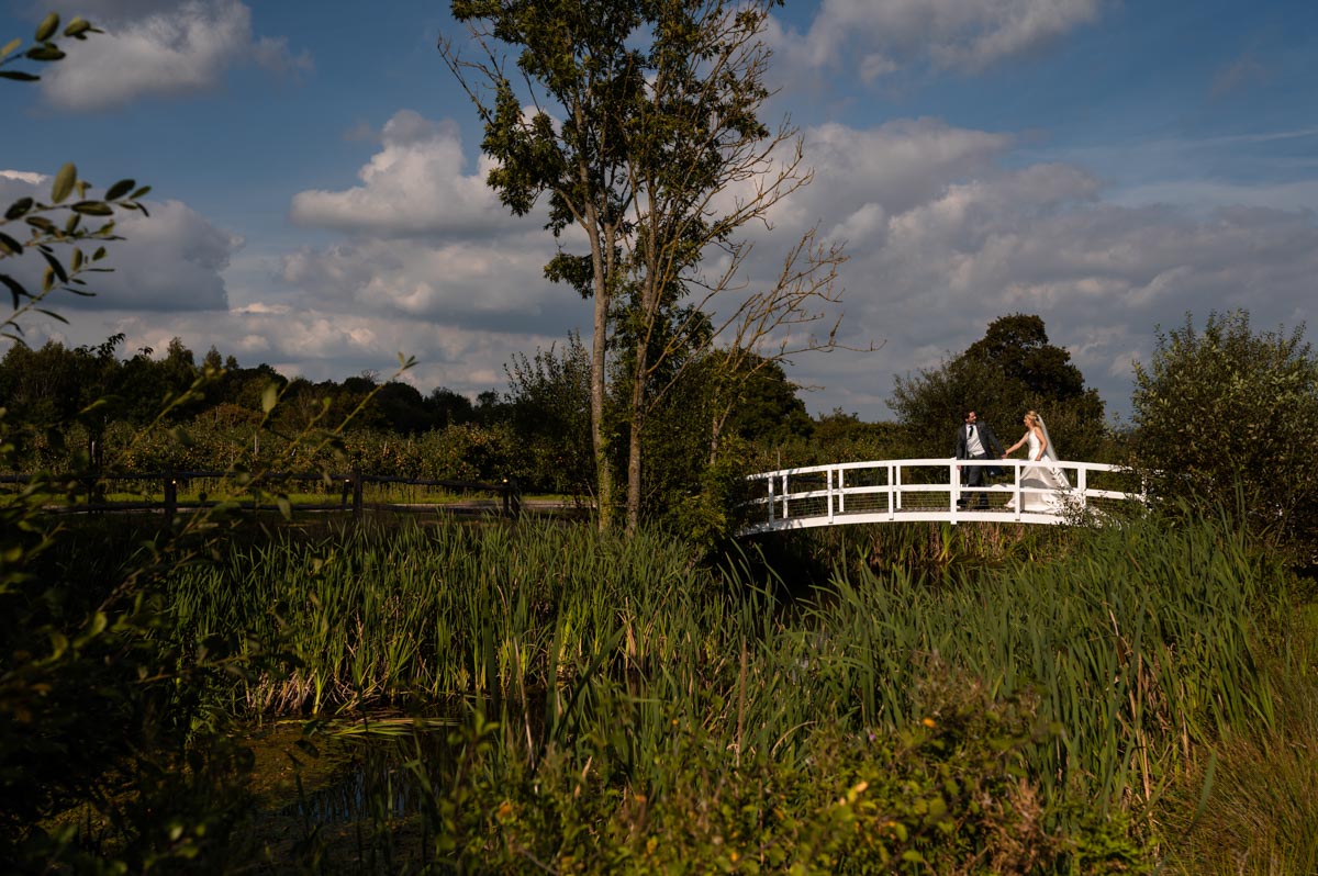 Photograph of Fiona and Chris as they cross the ornate bridge at The Cherry barn on their wedding day