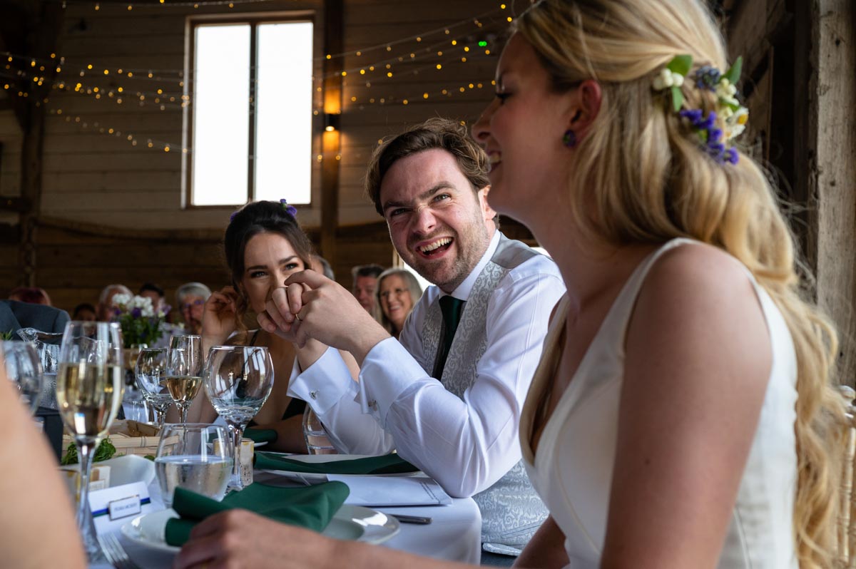 Photograph of bride and groom during speeches at their wedding at The Cherry Barn in East Sussex