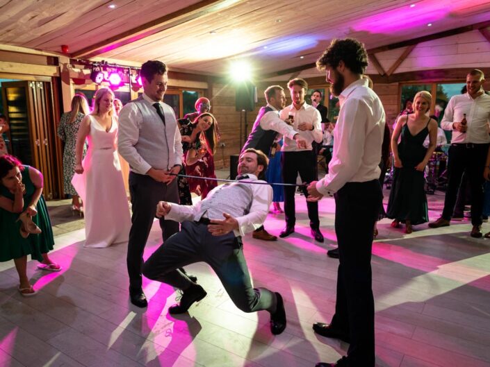 Groom photographed doing limbo dancing at The Cherry barn wedding venue
