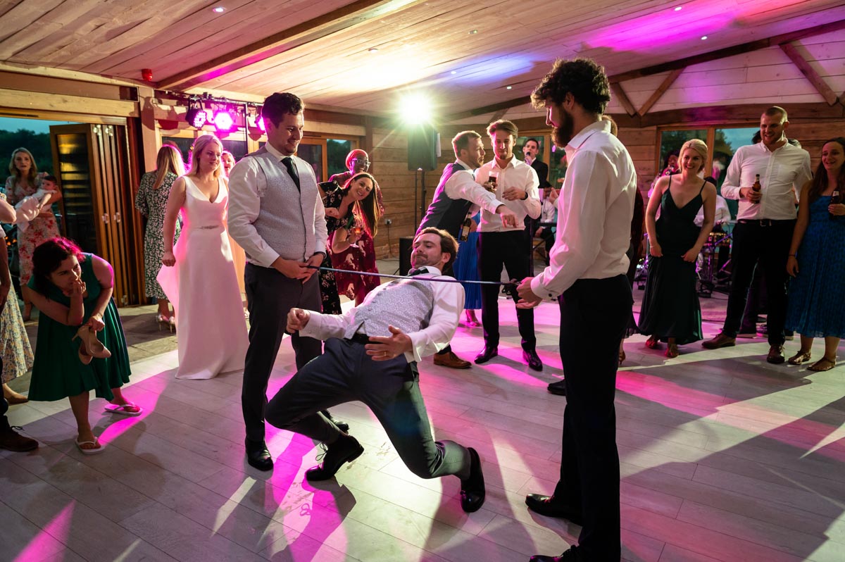 Groom photographed doing limbo dancing at The Cherry barn wedding venue
