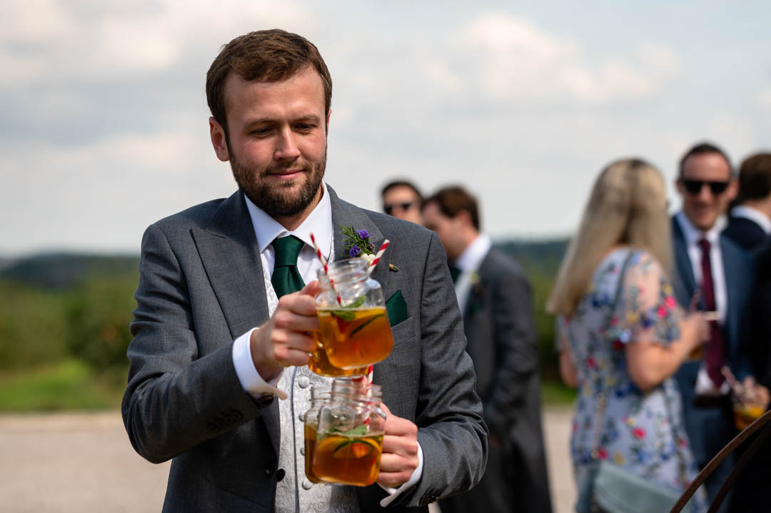 groomsman at Fiona and Chris's Cherry Barn wedding carrying pimms drinks