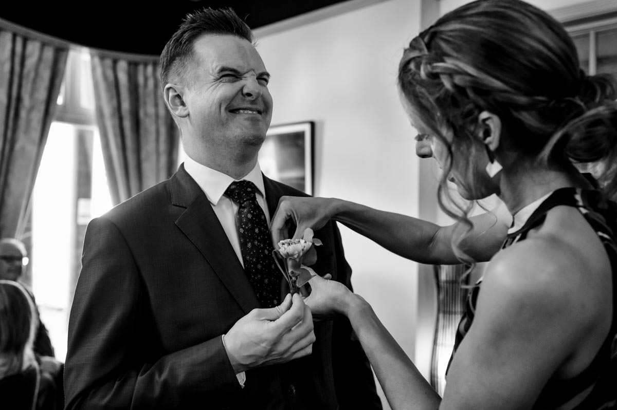 Black and white photo of wedding guest having buttonhole attached at Hythe Imperial wedding of Ann and Alan