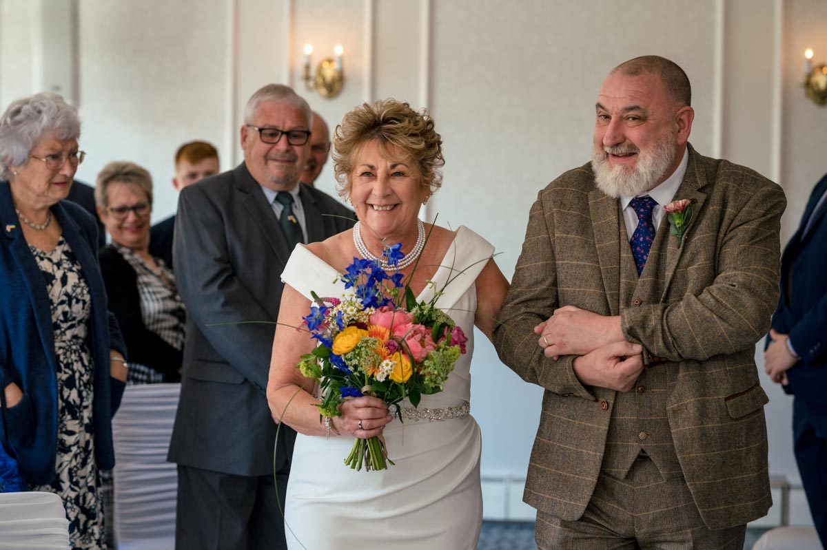 Photograph of Ann being walked down the aisle on her wedding day at the Hythe Imperial Hotel in Kent