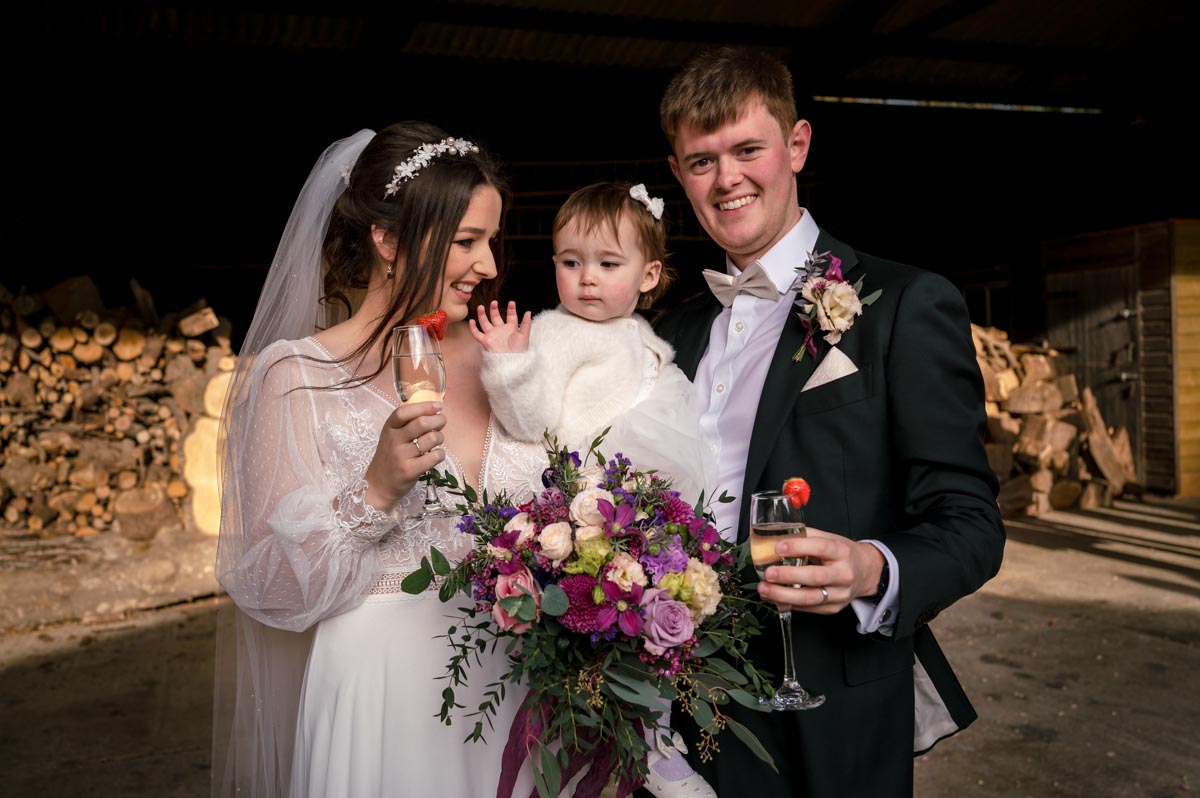 Bride and groom plus their daughter photographed outside at The Oak Barn, Frame farm wedding venue in Kent