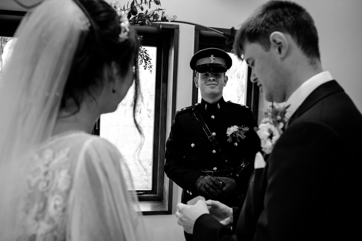 Black and white photograph of Will, Sophia and best man during their wedding ceremony at The Oak Barn, Frame Farm, Kent