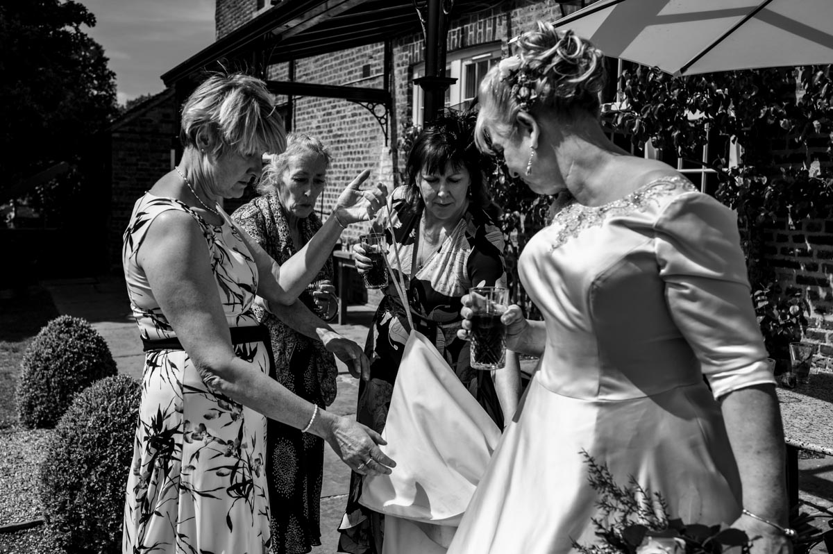 bride and friends adjust wedding dress at the secret garden in ashford, kent