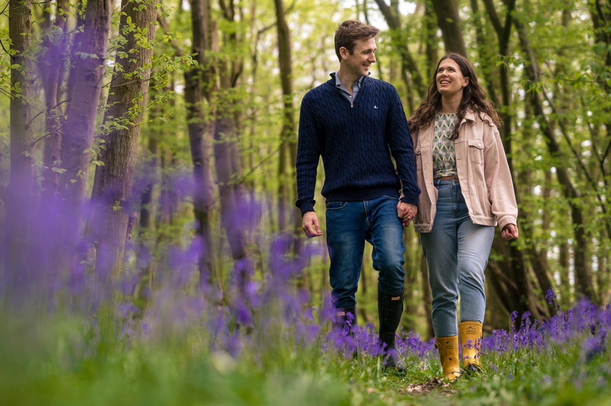 Becca and fred walk hand in hand through bluebell woods during their pre wedding photoshoot in Kent