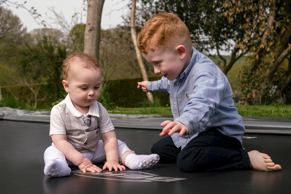 Rupert and cousin play on trampoline after his christening in Kent
