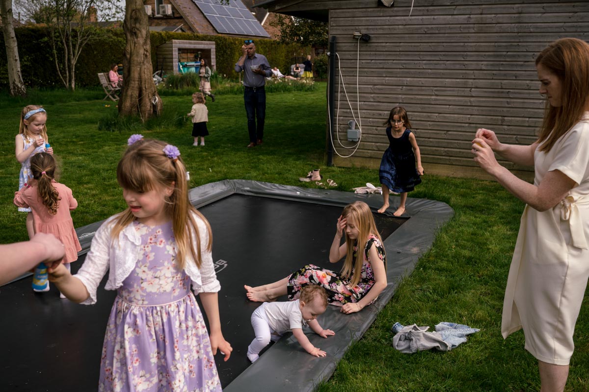 Children photographed playing on trampoline after christening service