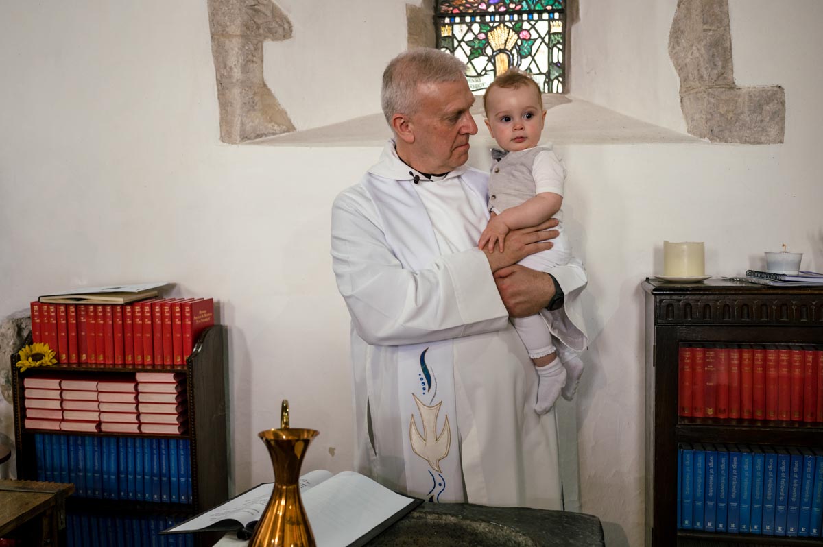 Christening photography Kent. vicar and Rupert by the font