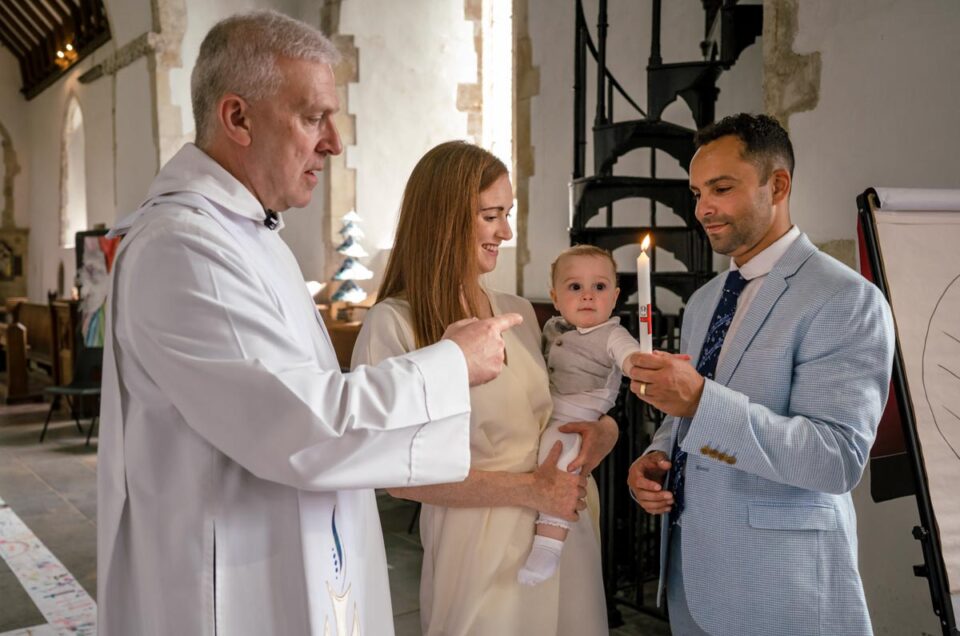 Christening photography Kent. Vicar presenting candle to Ruperts family