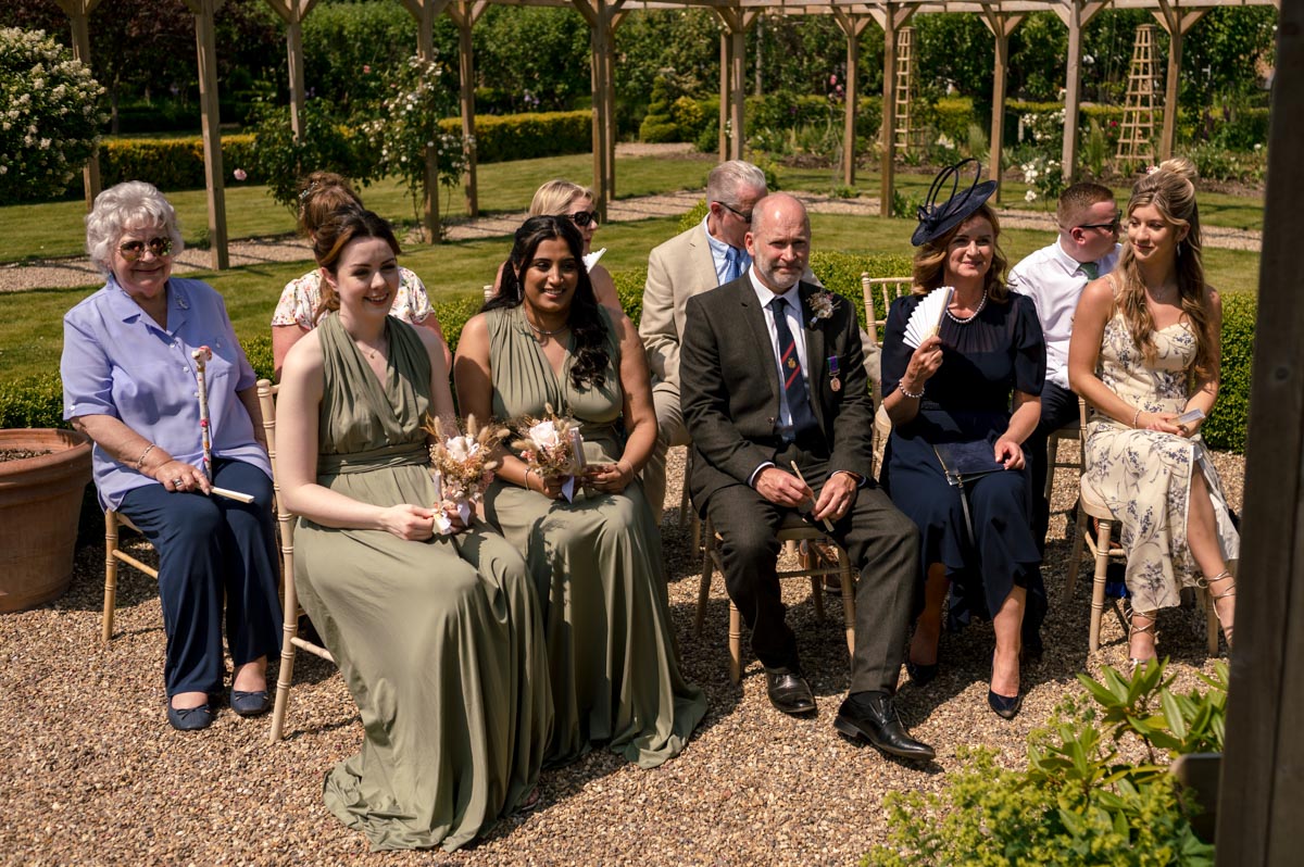 photograph of wedding guests outside at the secret garden during ceremony in gazebo