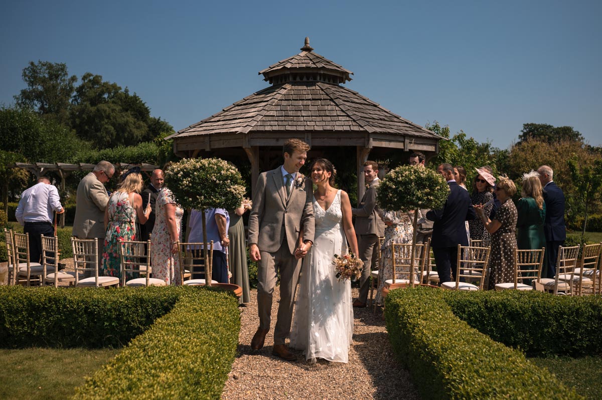 fred and becca walk back down the aisle after their wedding in the gazebo at the secret garden in kent
