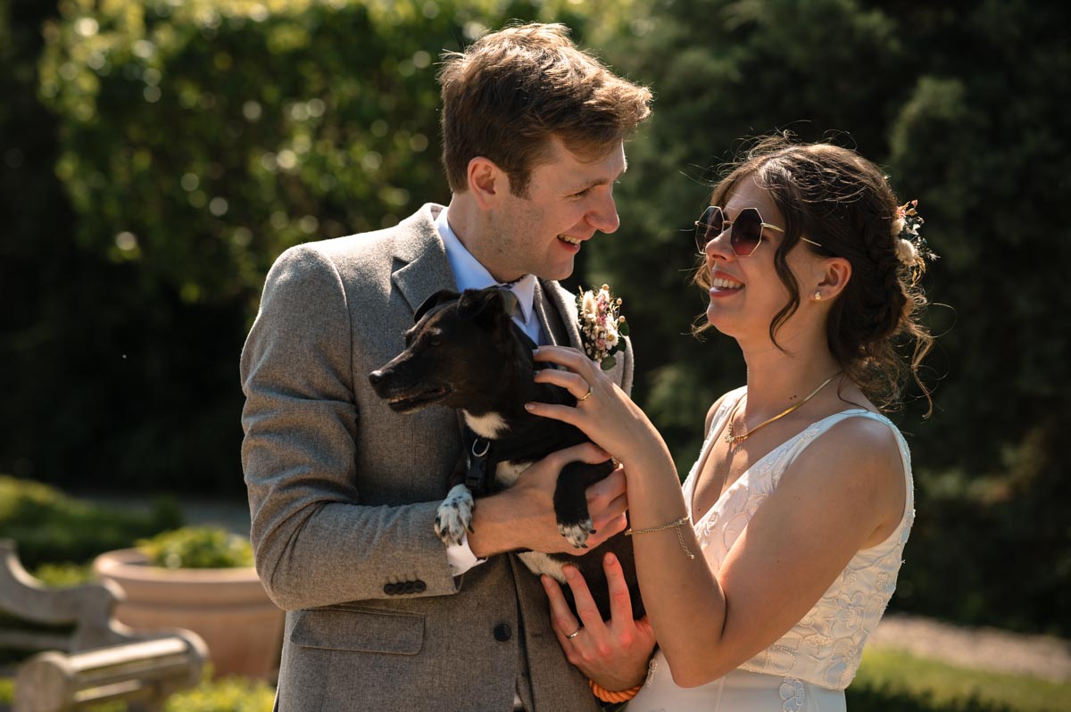 wedding photograph of becca and fred with their dog in the secret garden after their wedding ceremony