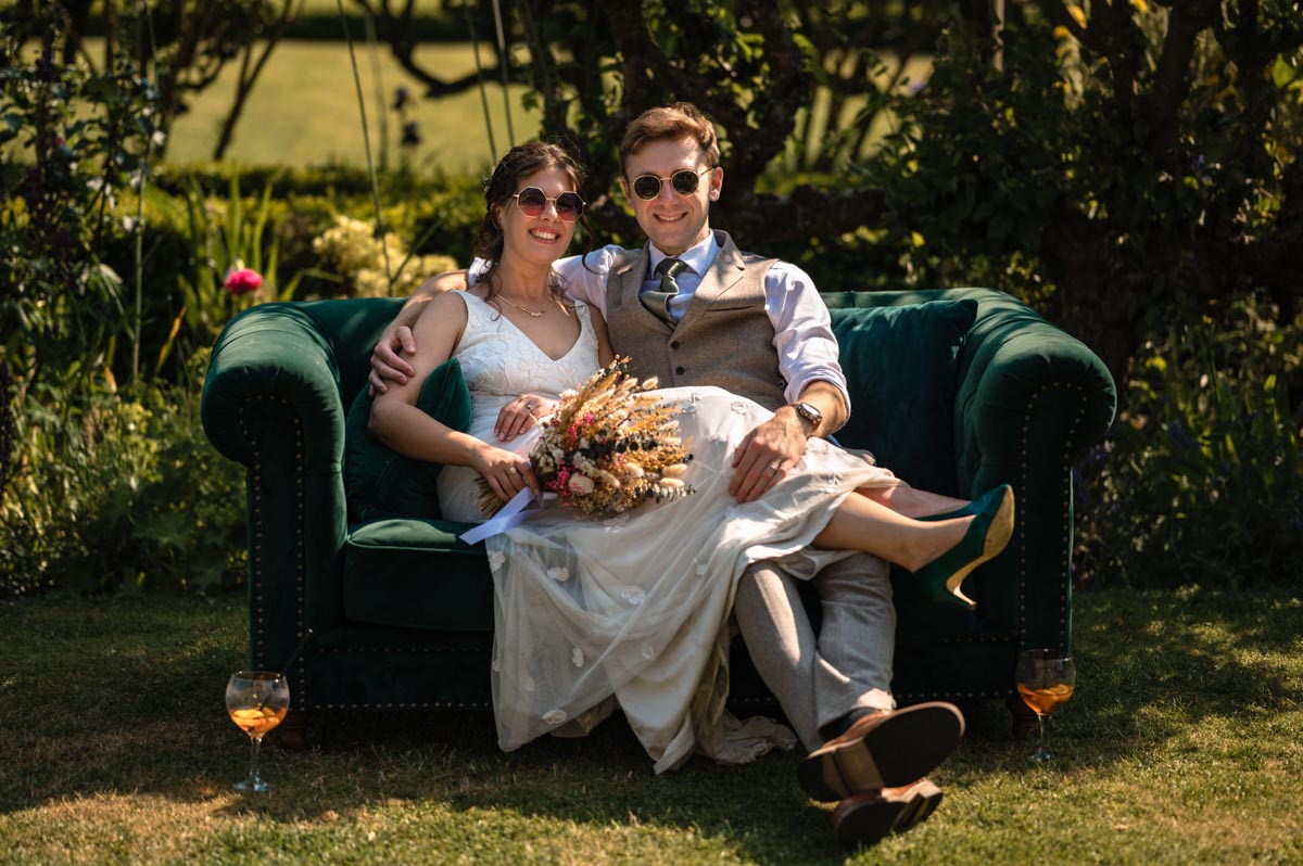 photograph of fred and becca on the green sofa outside at the secret garden in kent