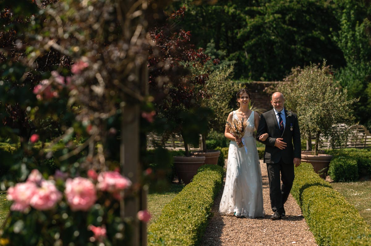 becca and her father walk down the aisle at her secret garden wedding in kent