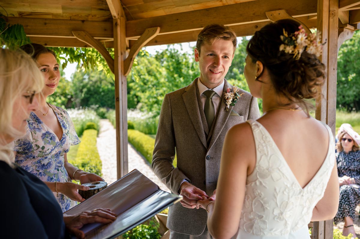 photograph of fred placing ring on beccas finger during secret garden wedding ceremony