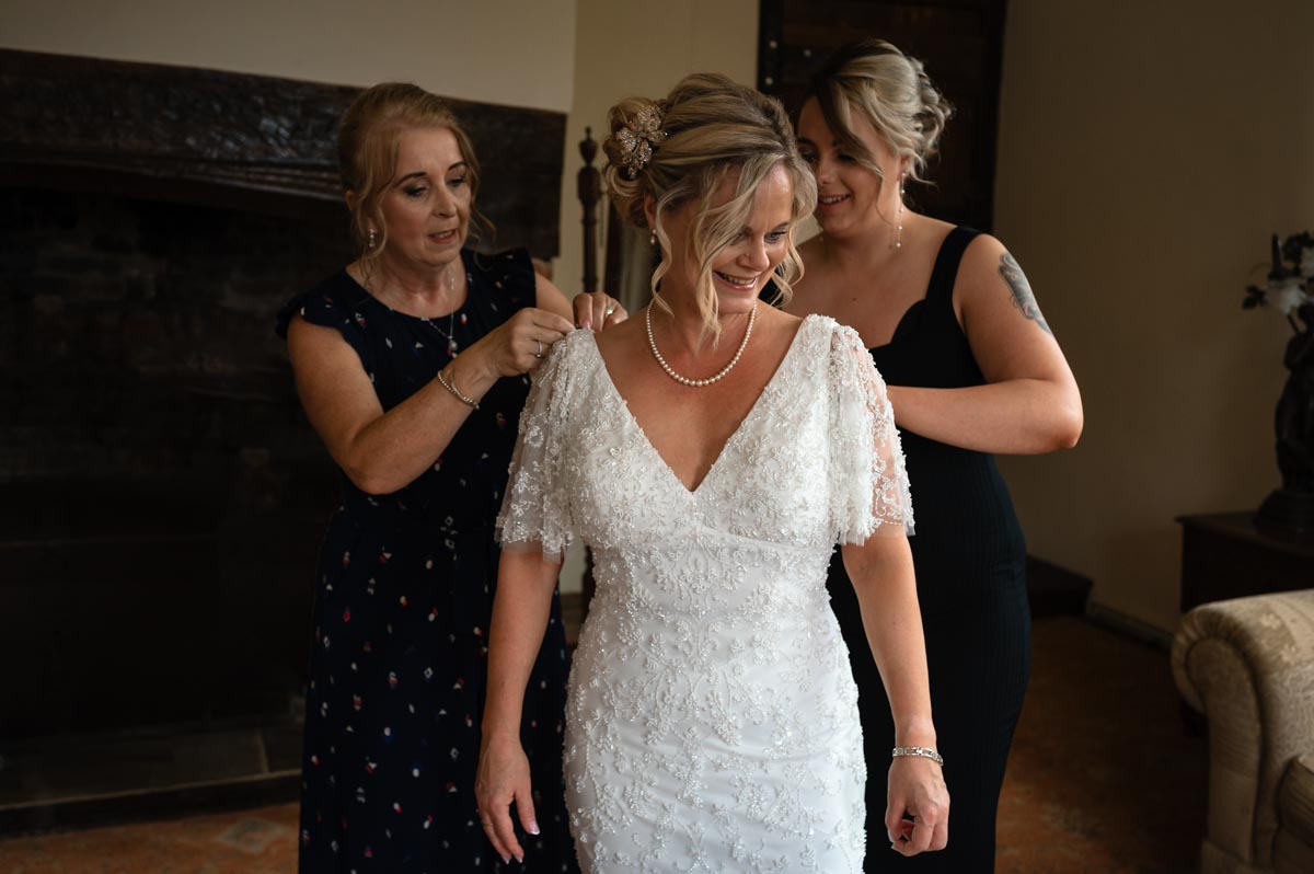 Bridesmaids help Lara with wedding dress before her westenhanger castle wedding