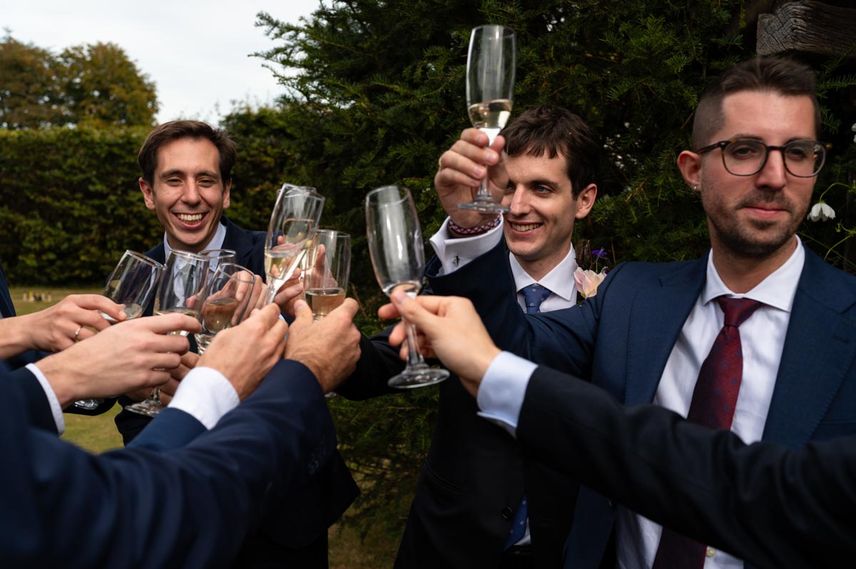 Groom and friends have a drink at Bilsington Priory wedding in Kent