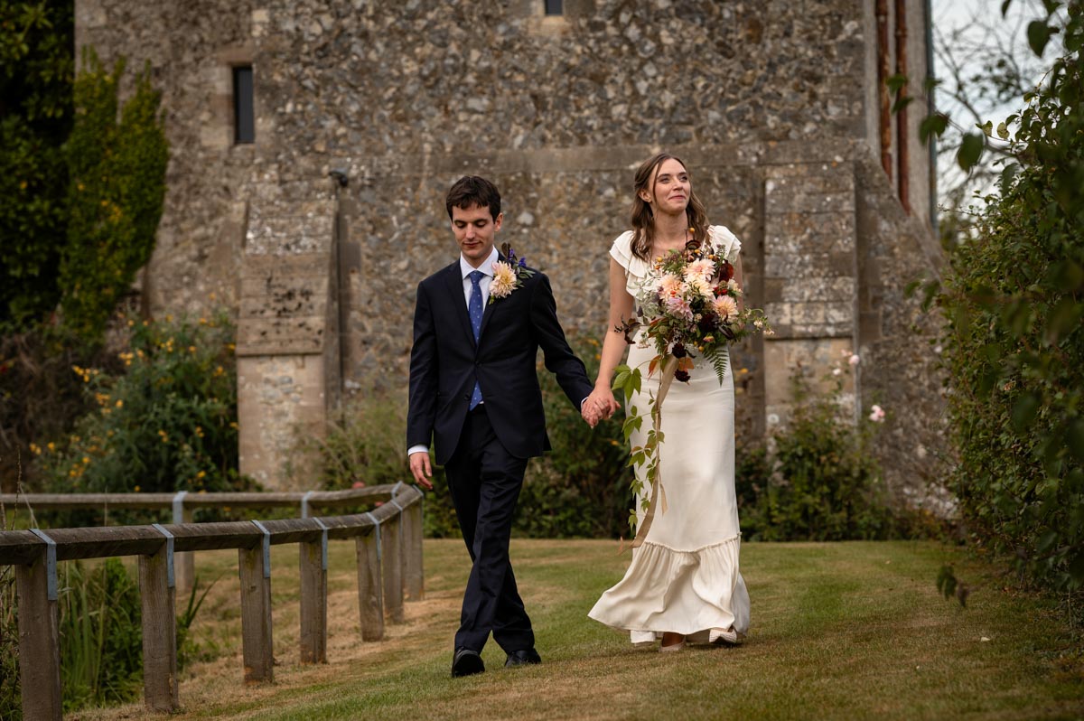 Poppy and Pablo walk hand in hand at their Bilsington Priory wedding