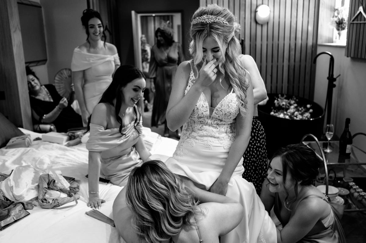 Sarah giggles while bridemaids fix her dress