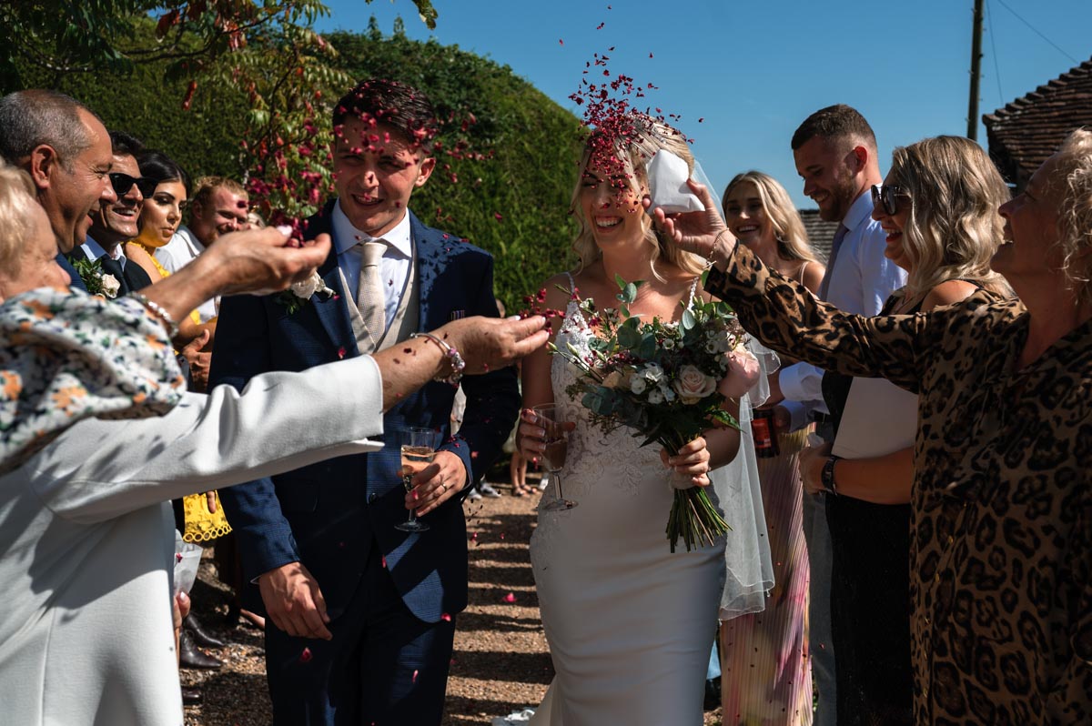 Sarah and James photographed with confetti being thrown on them at their swallows oast wedding