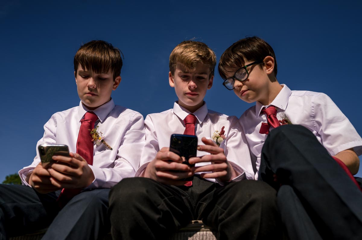 Photograph of boys on their phones at Sarah and Matthews wedding at Little Bayham in Kent