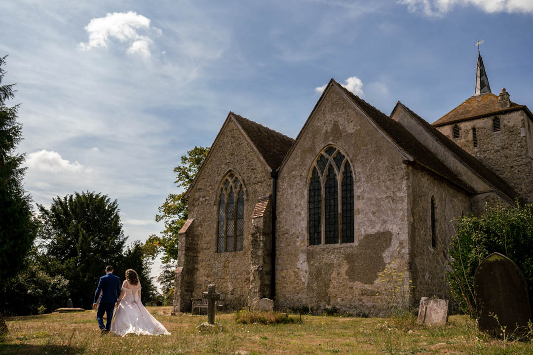 jad and Richard walk together in the churchyard after their small wedding ceremony in Kent